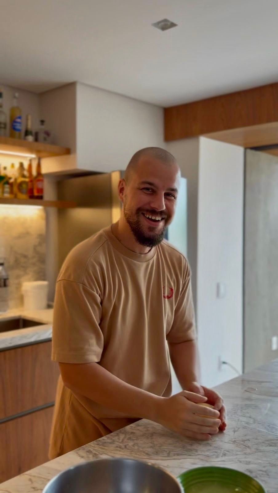 O chef da Baiocchi na cozinha, sorrindo apoiado à bancada de mármore.