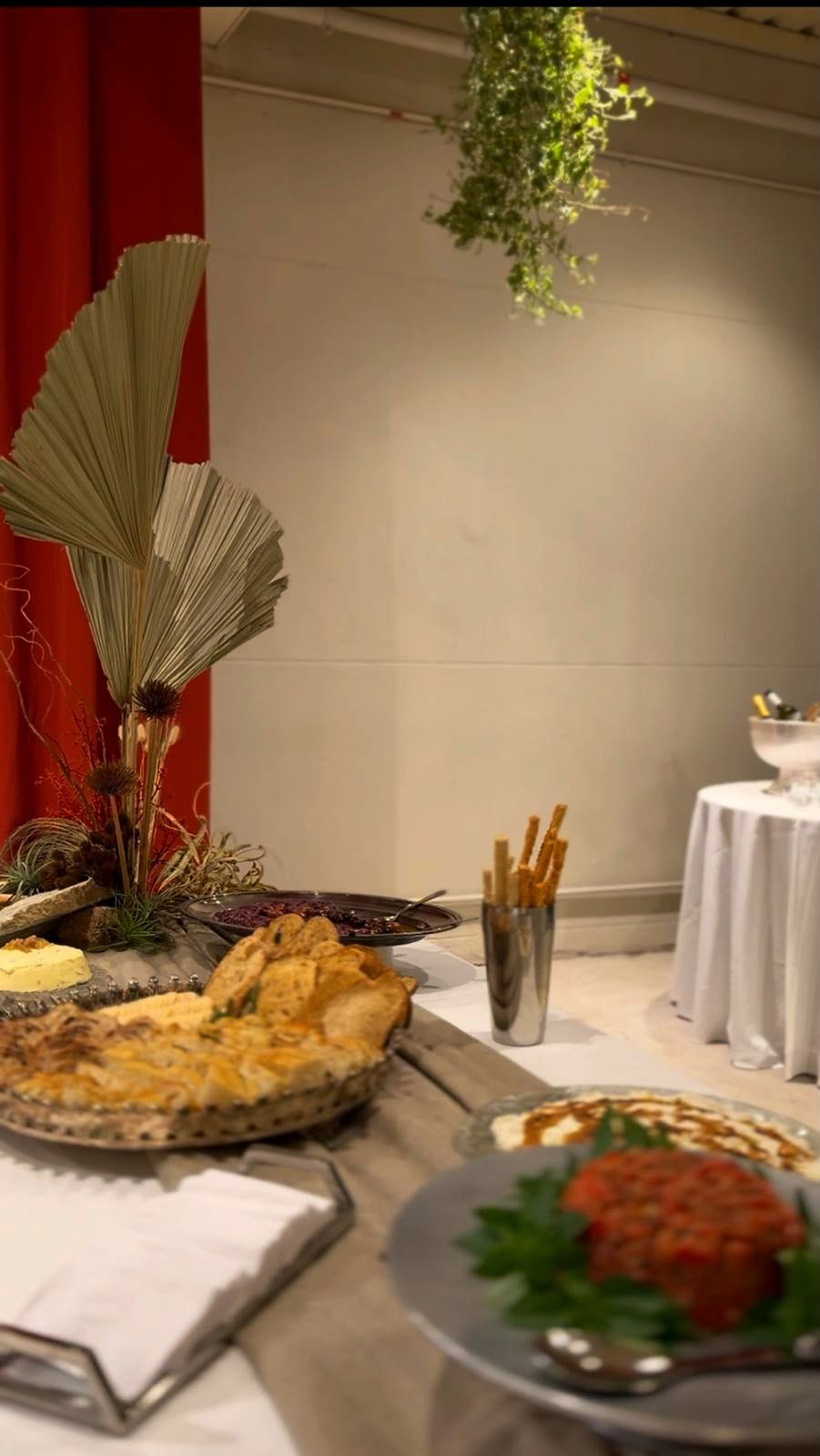 Mesa posta do evento com arranjo de folhas secas, pães artesanais, pastas e tartare de tomate.