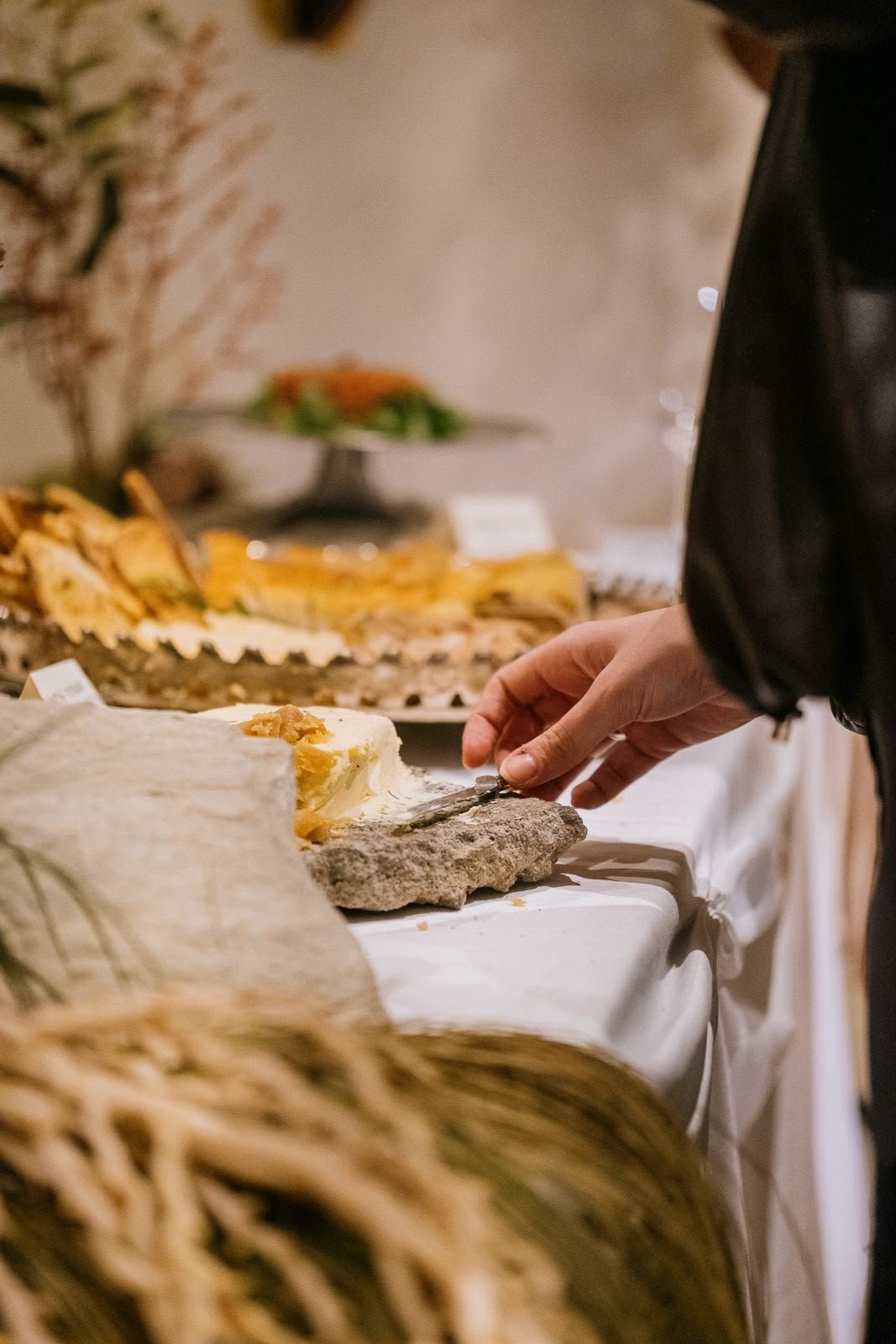 Detalhe do buffet: queijo cremoso servido sobre pedra, ao lado de pães e torradas.
